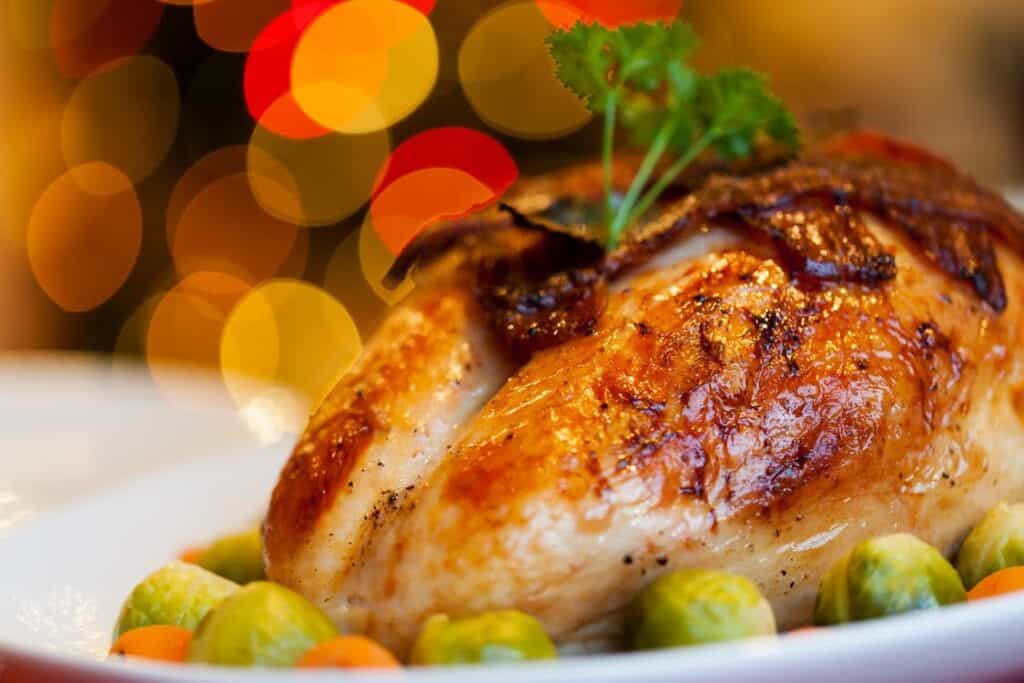 A plated roasted chicken surrounded by vegetables.