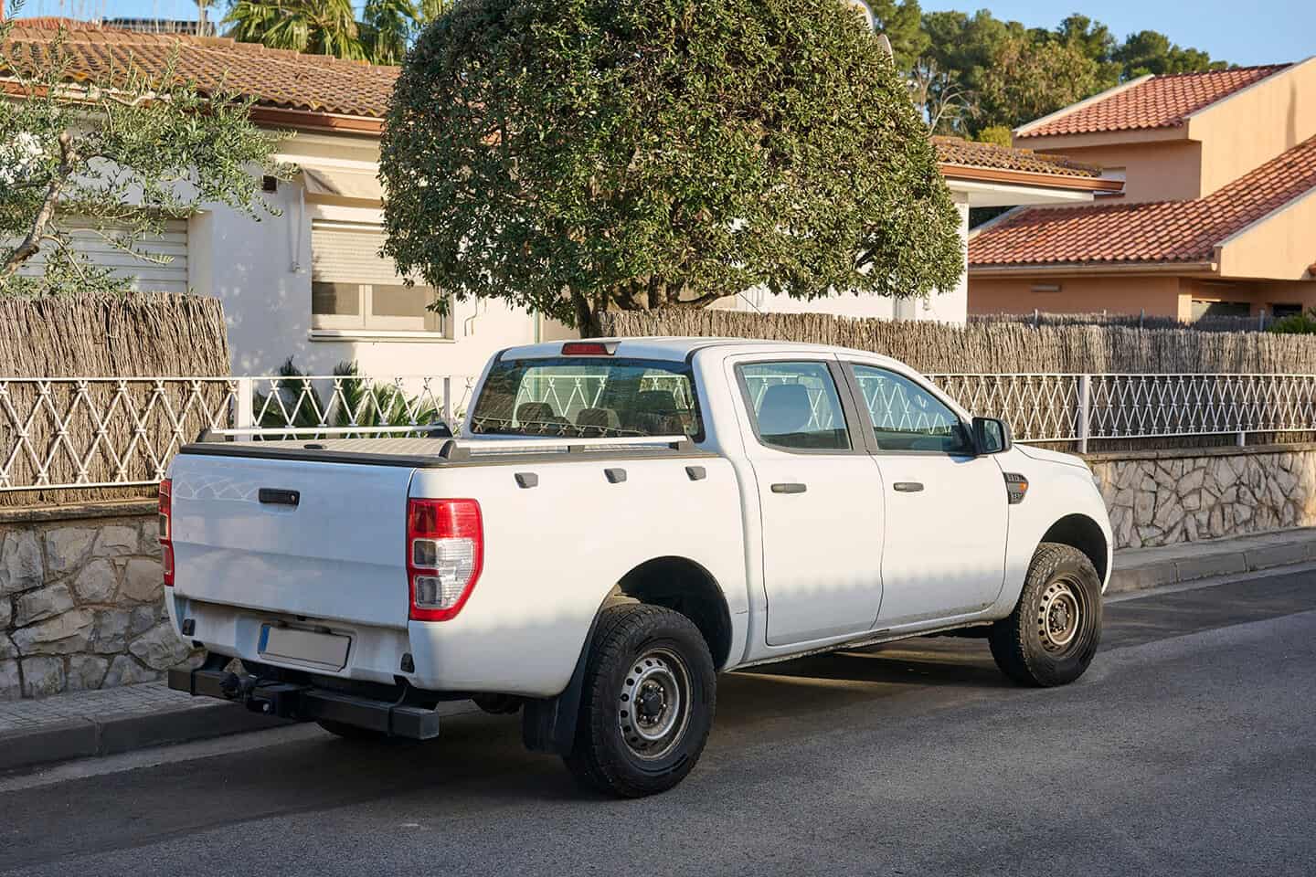 A white truck parked on the side of the street in a community neighborhood.